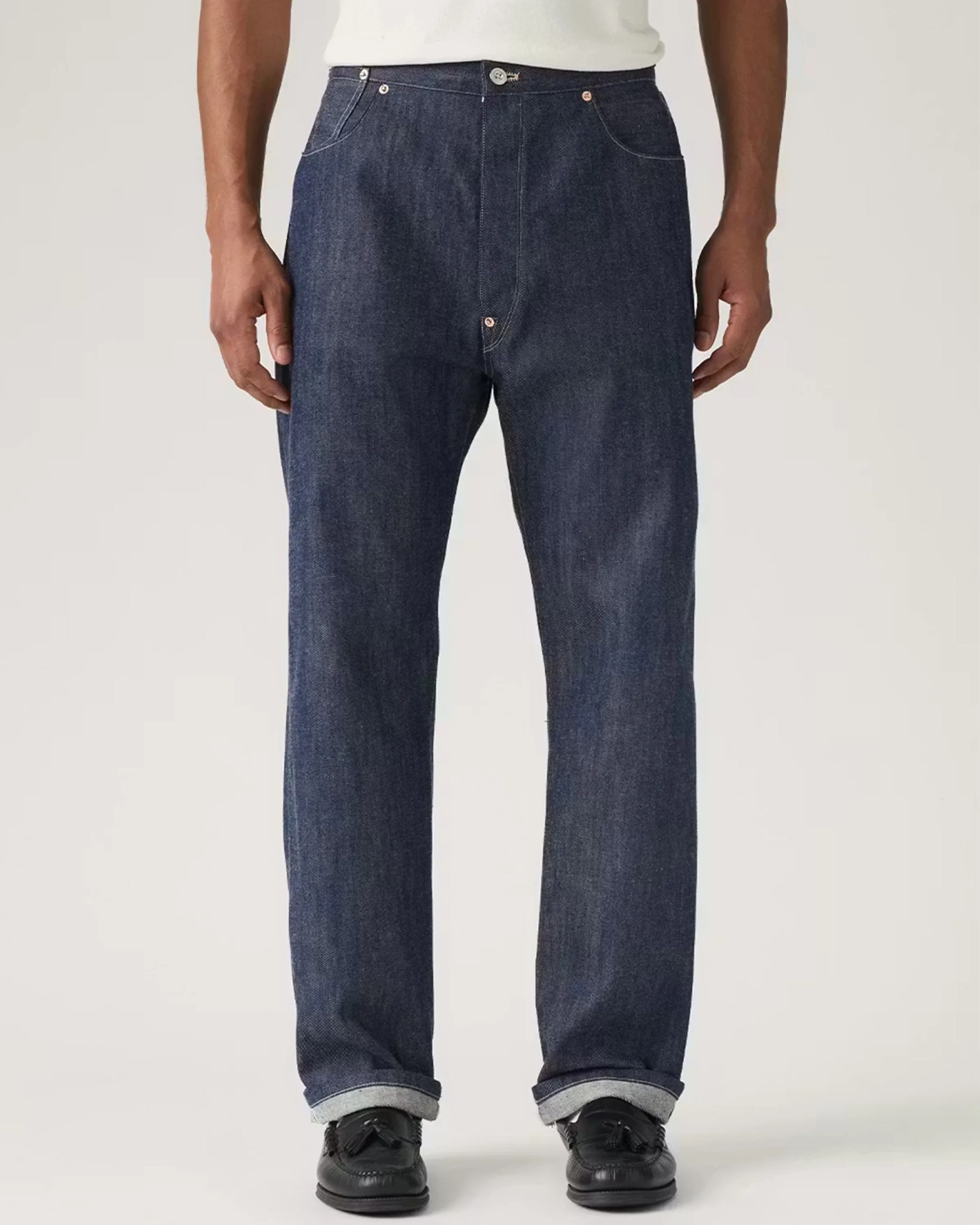Dark blue straight-leg denim jeans with rolled cuffs worn with black tassel loafers.