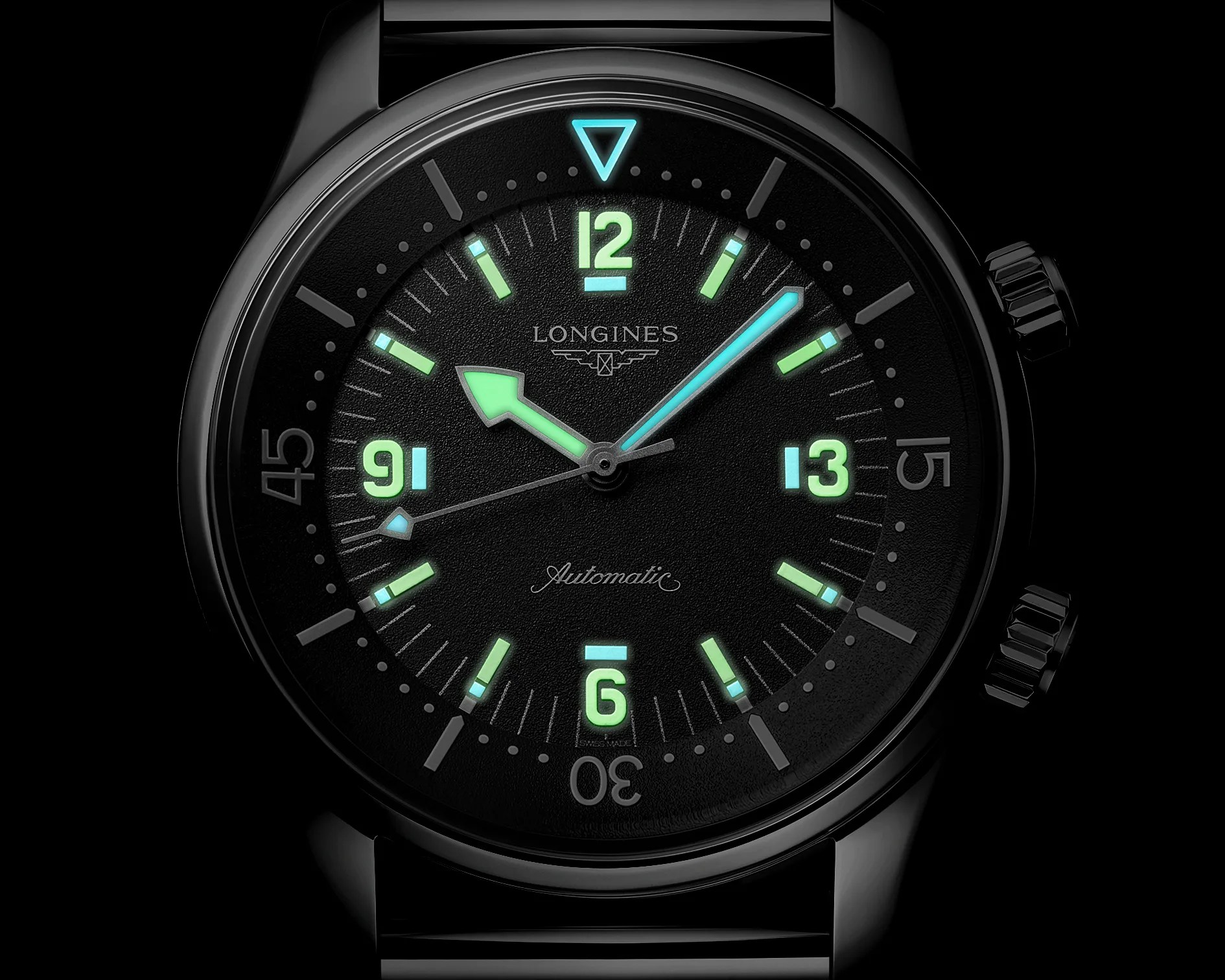 Black Longines watch face with luminescent green and blue hour markers and hands, showing time 10:08:42.