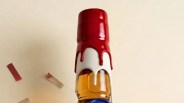 Top of a glass bottle with red and white wax dripping down the neck against a beige background.