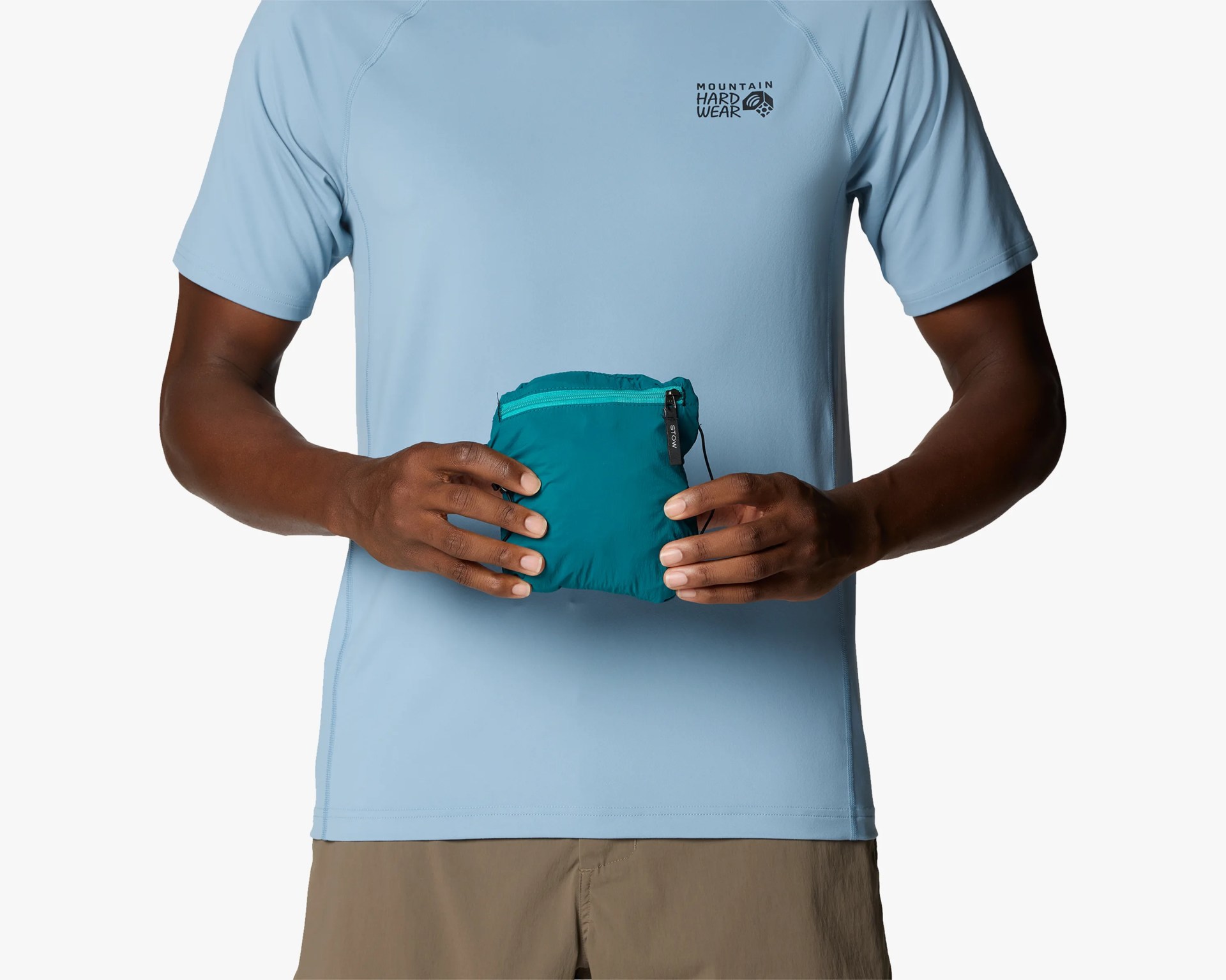 Teal compact zippered pouch held by a person wearing a light blue Mountain Hardwear shirt and tan pants.