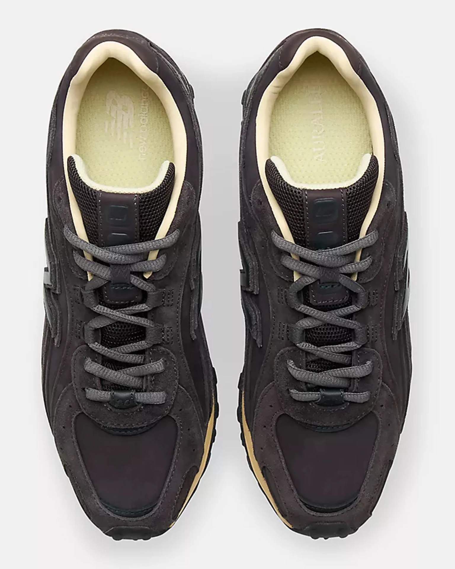 Pair of dark gray New Balance sneakers with beige inner lining and gray laces viewed from above.