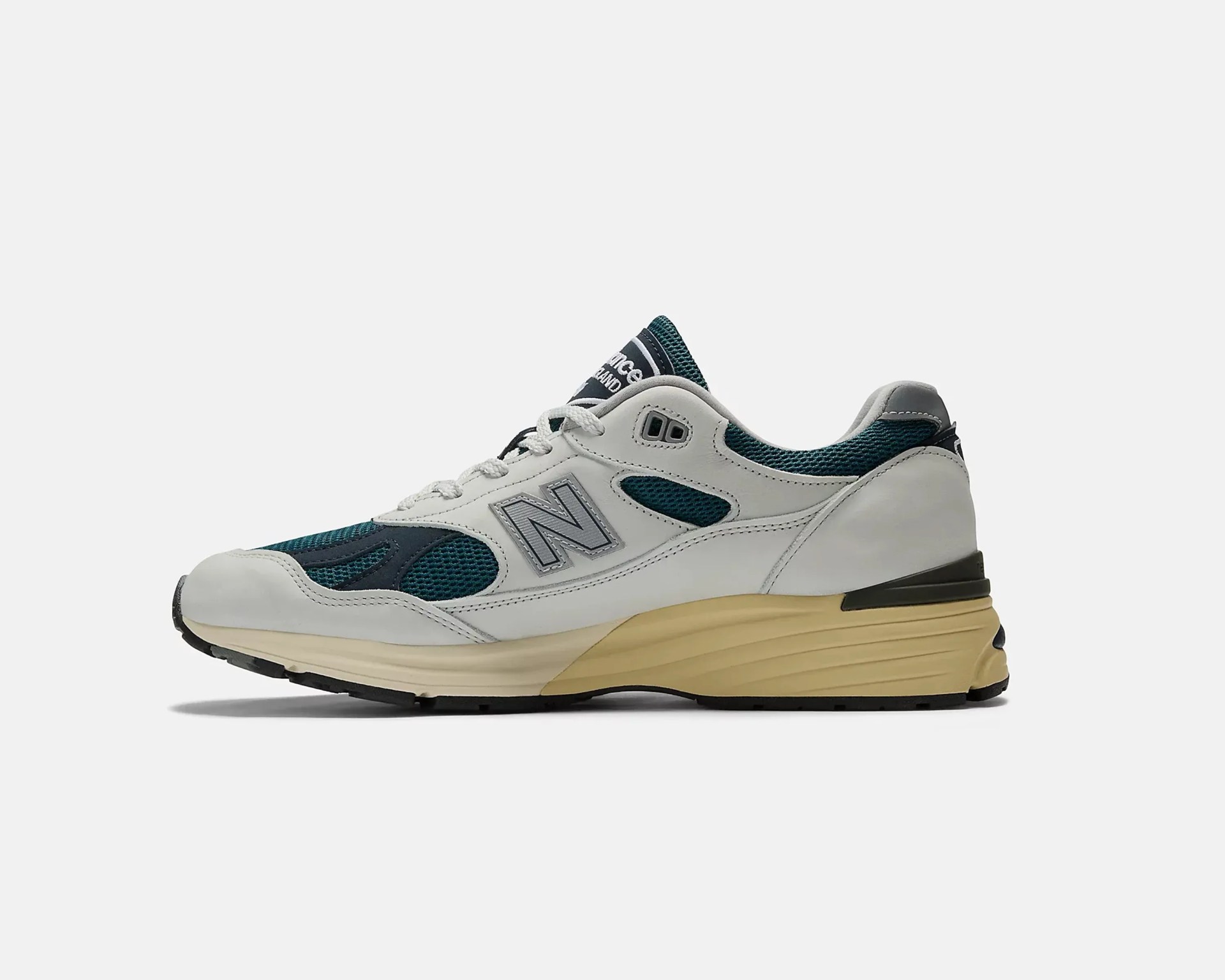 White and dark teal New Balance sneaker with mesh panels and beige sole viewed from the side.