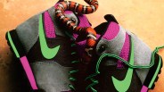 Pair of gray and purple Nike sneakers with green swooshes and laces, with a red and black snake coiled on them.