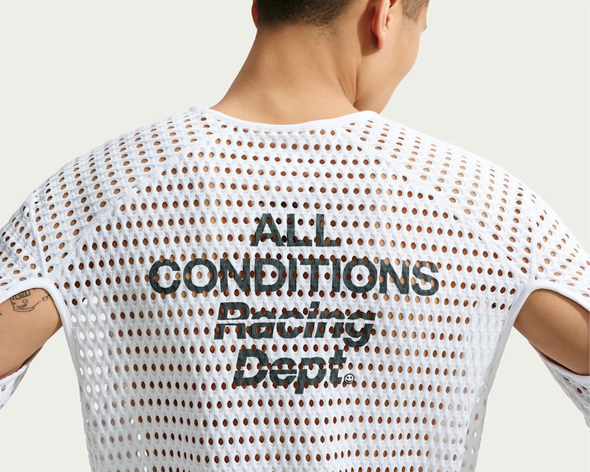 White mesh sleeveless top with black text "ALL CONDITIONS RACING DEPT." on the back, worn by a person.