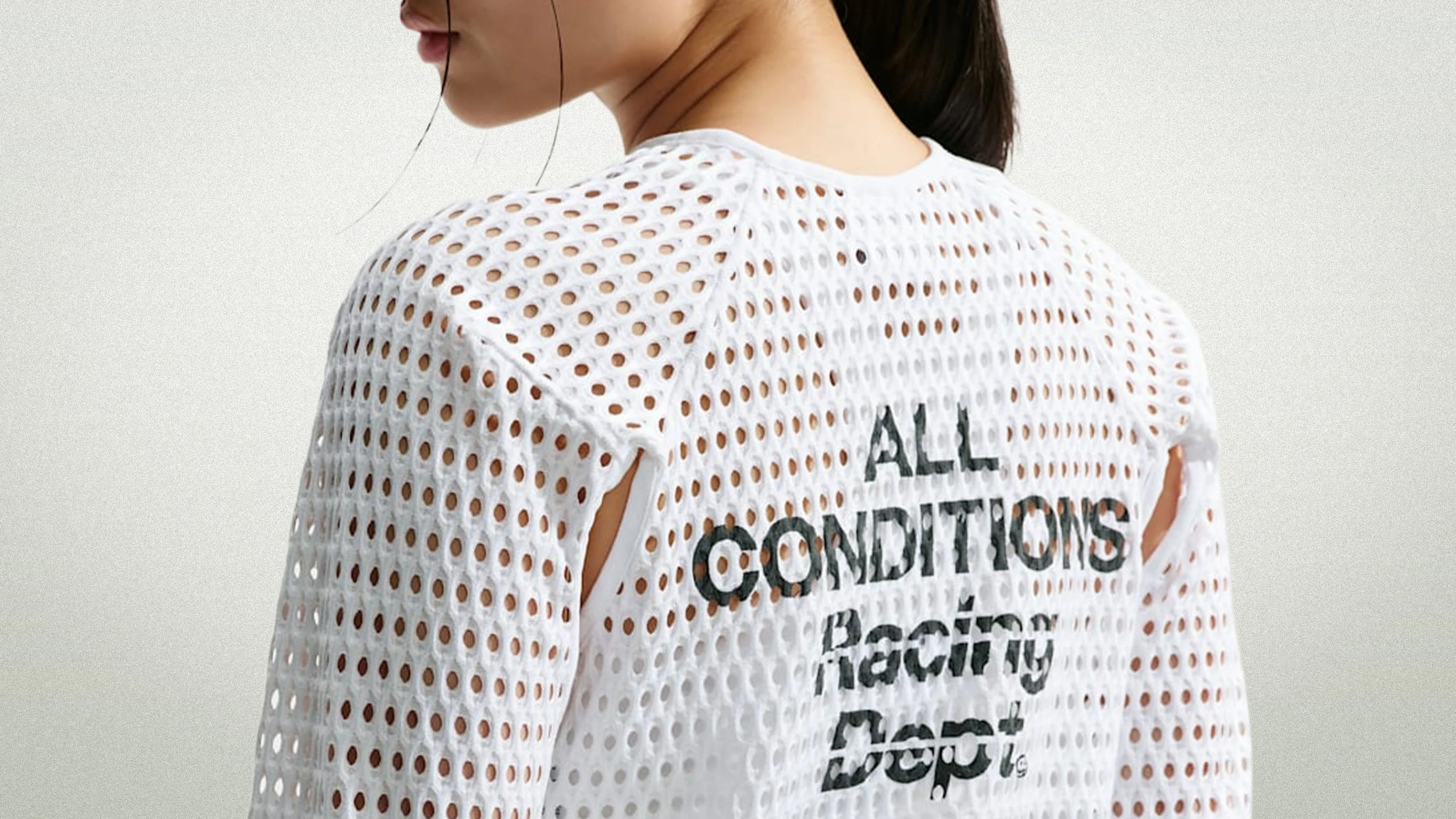 White mesh top with large holes and black text reading "ALL CONDITIONS Racing Dept." on the back, worn by a person.