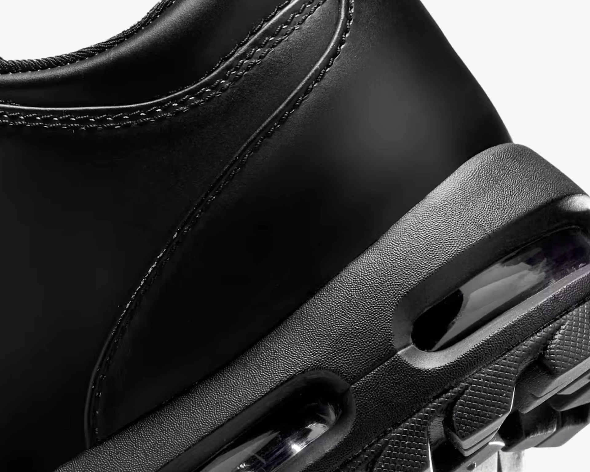 Close-up of a black sneaker's heel with textured midsole and visible air cushioning unit.