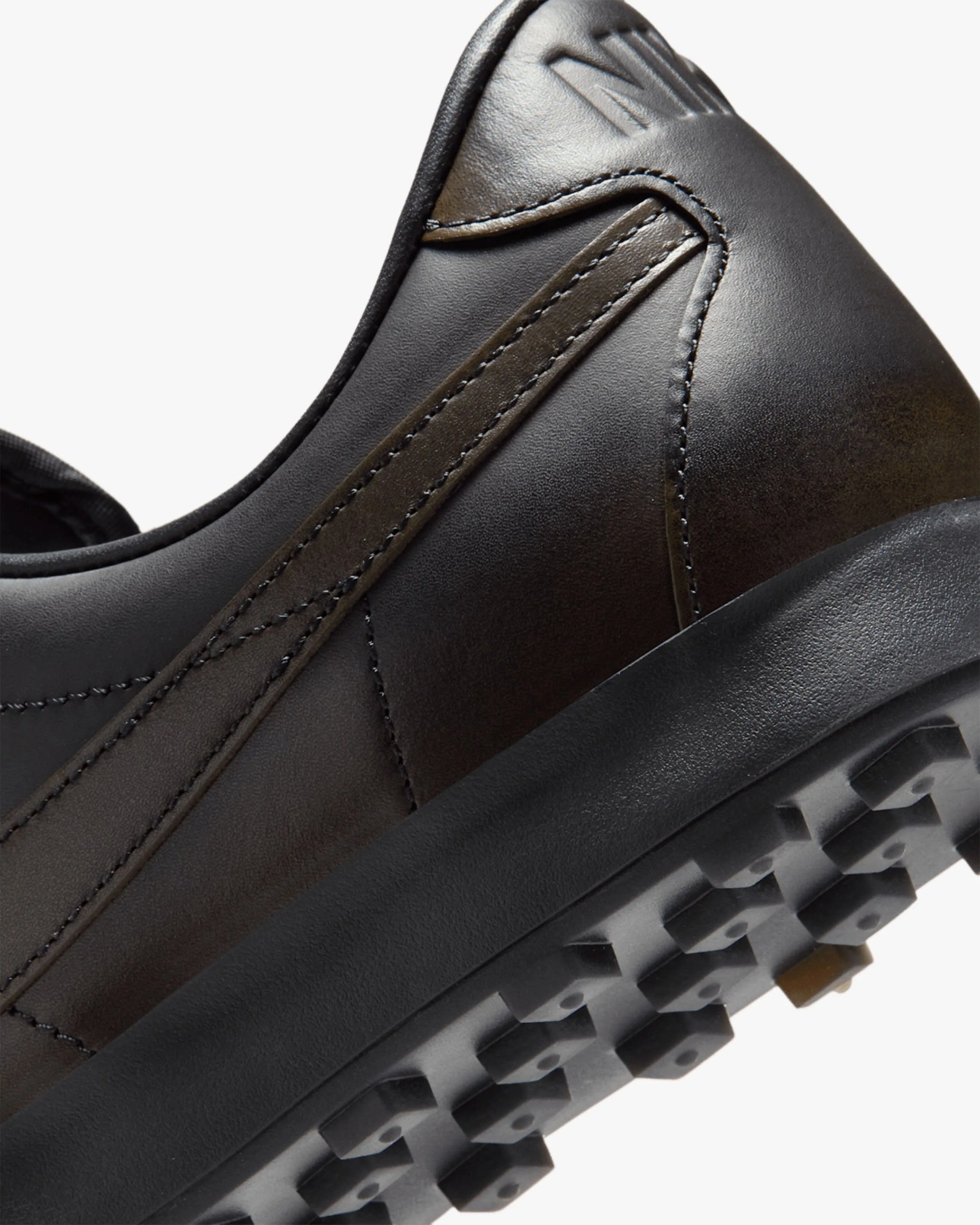Close-up of the heel and sole of a black leather sneaker with textured rubber outsole and stitched detailing.
