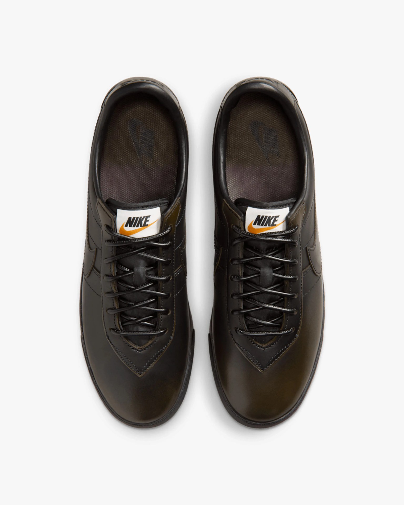 Pair of black Nike leather sneakers with black laces and white tongue labels featuring the Nike logo.