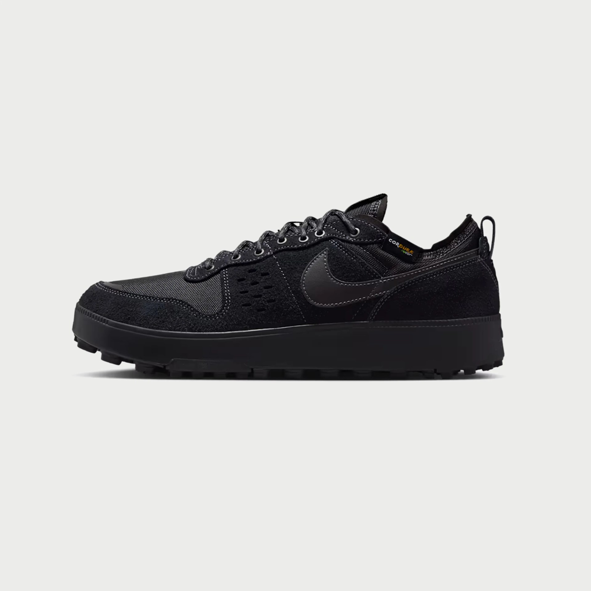 Black Nike sneaker with suede and mesh upper, black laces, and rugged sole.