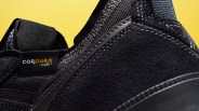 Close-up of black sneaker heel with Cordura fabric label and detailed stitching on a yellow background.