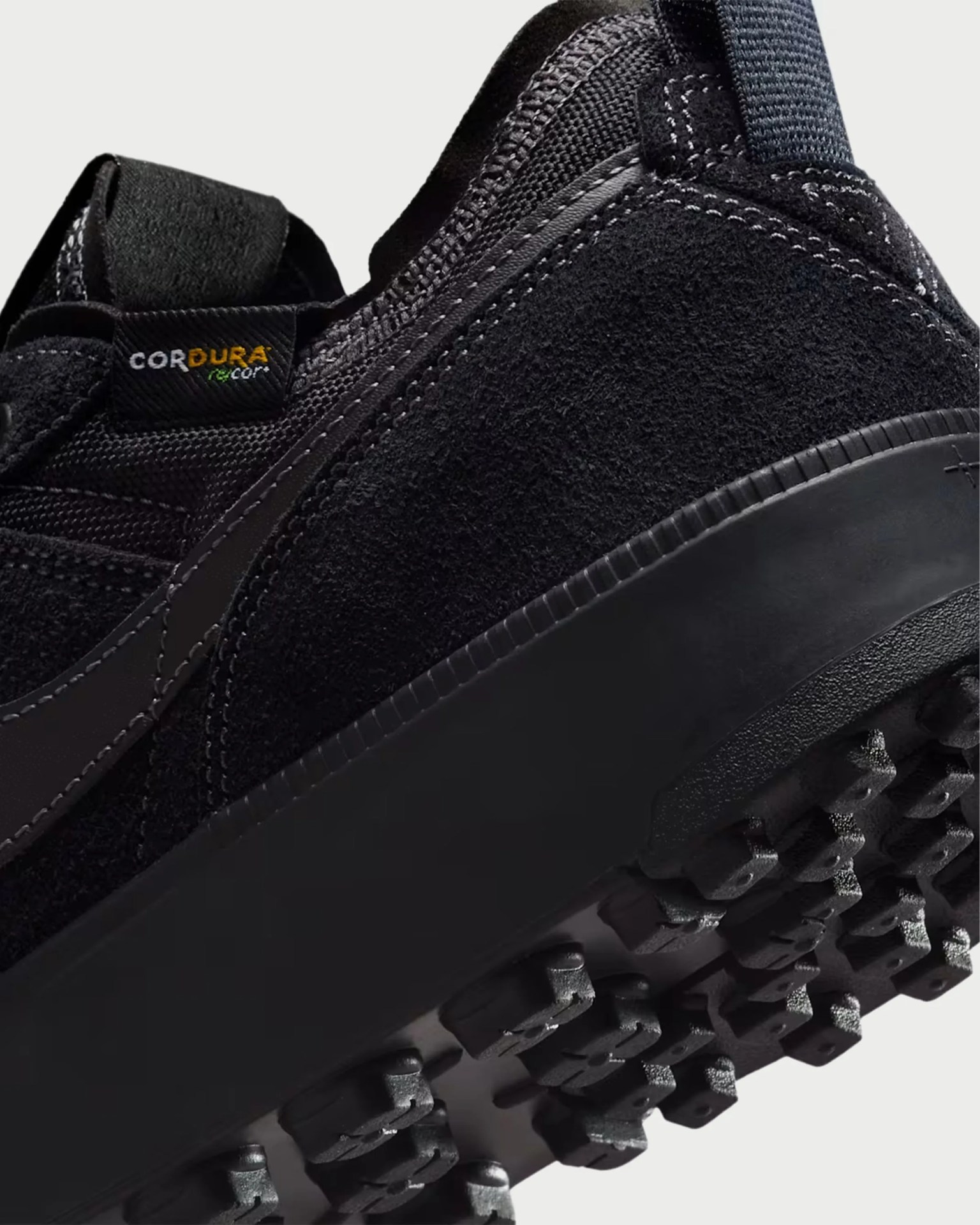 Close-up of a black sneaker with Cordura fabric tag and textured rubber sole.