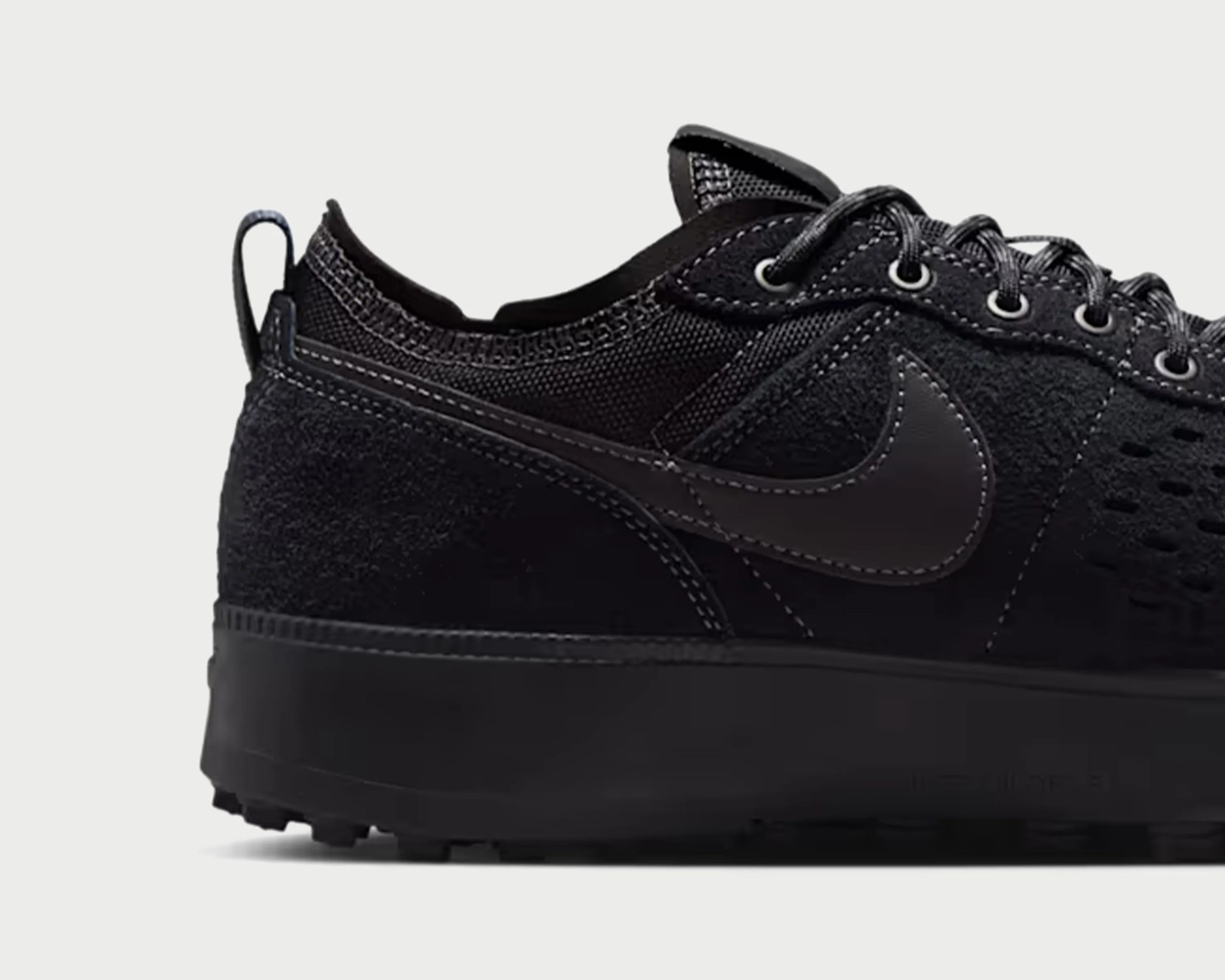 Black Nike sneaker with suede and mesh upper, black swoosh logo, and thick black sole.