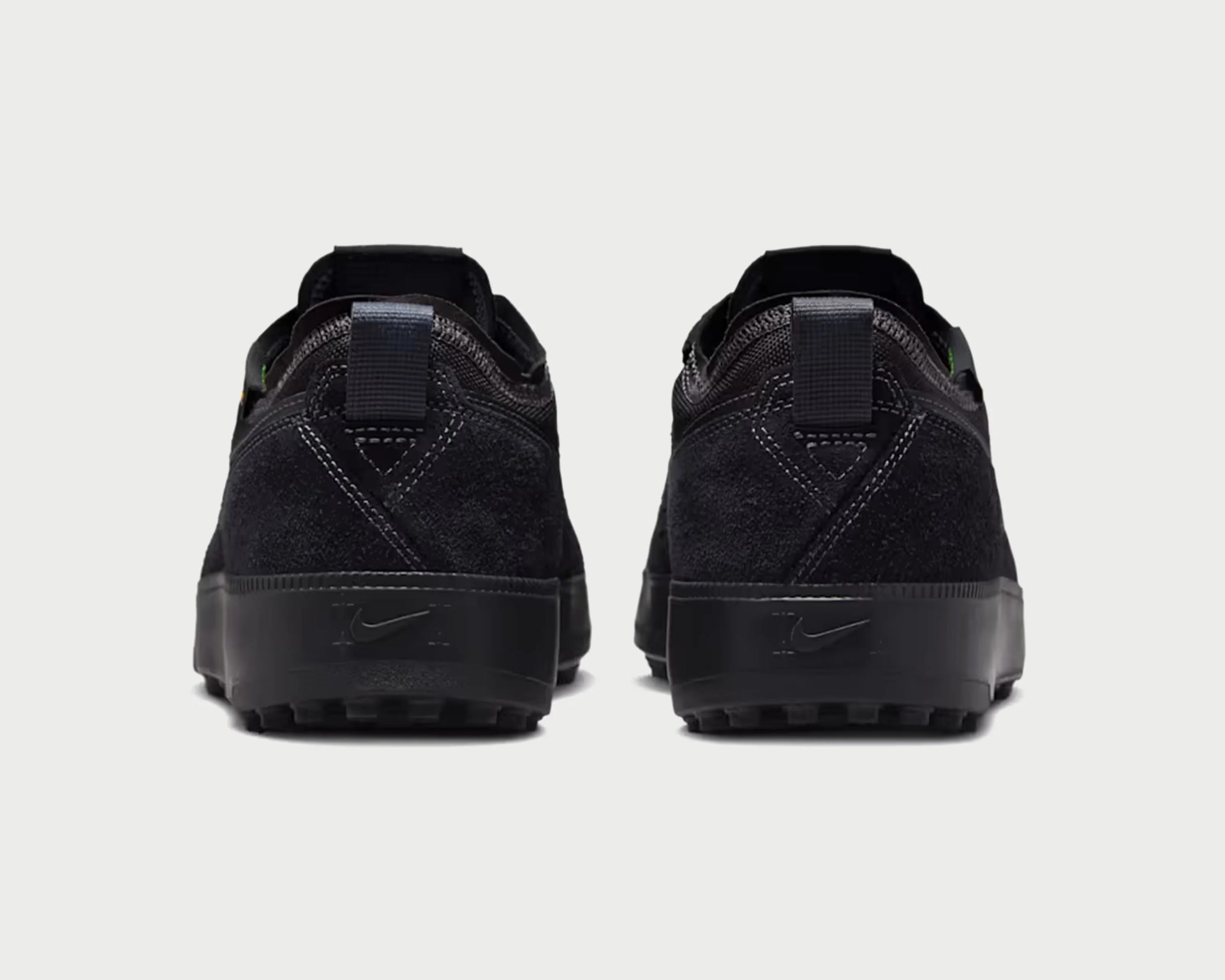 Pair of black Nike sneakers shown from the back with suede upper and pull tabs on the heel.
