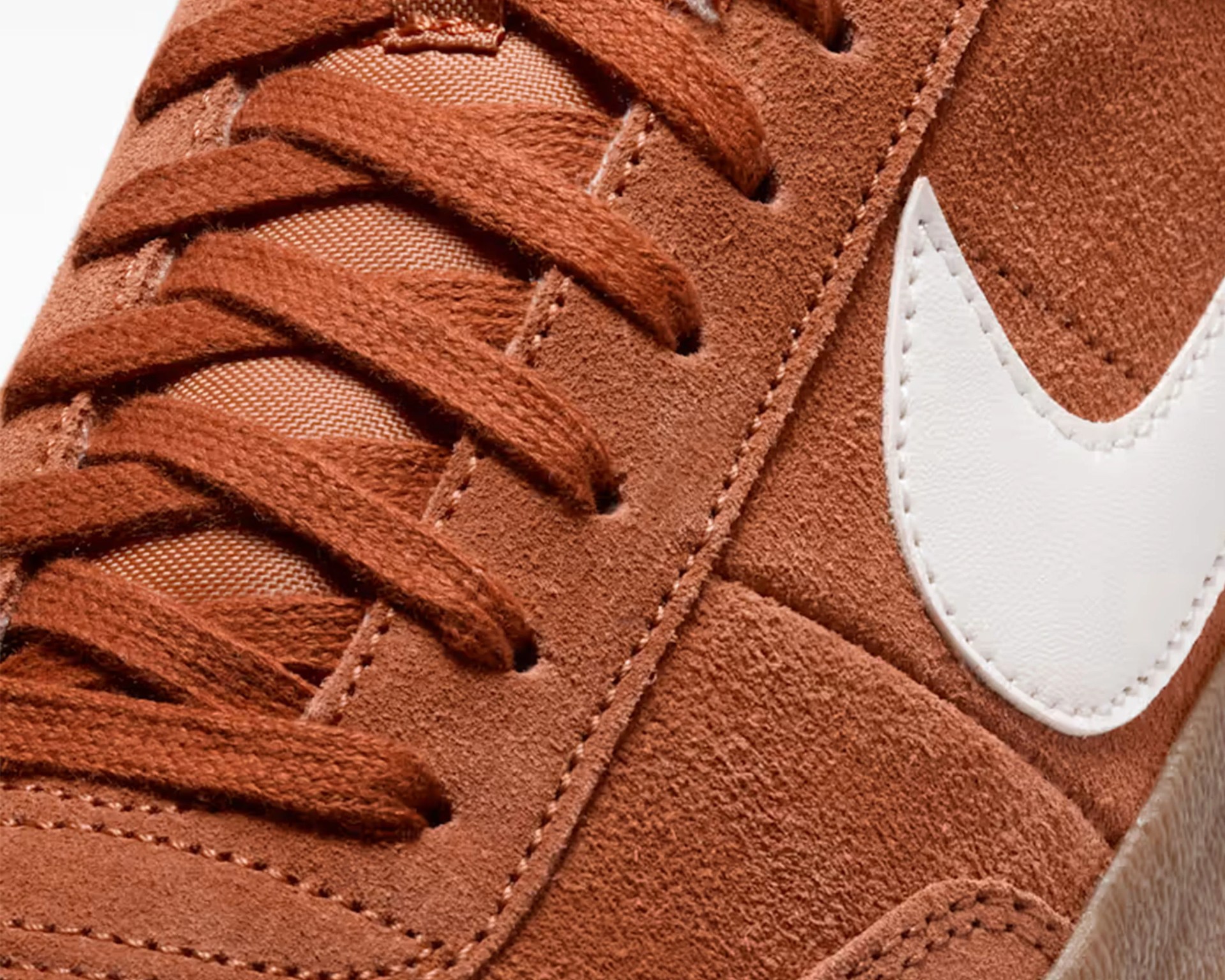Close-up of rust-colored suede sneaker with matching laces and a white stitched Nike swoosh.