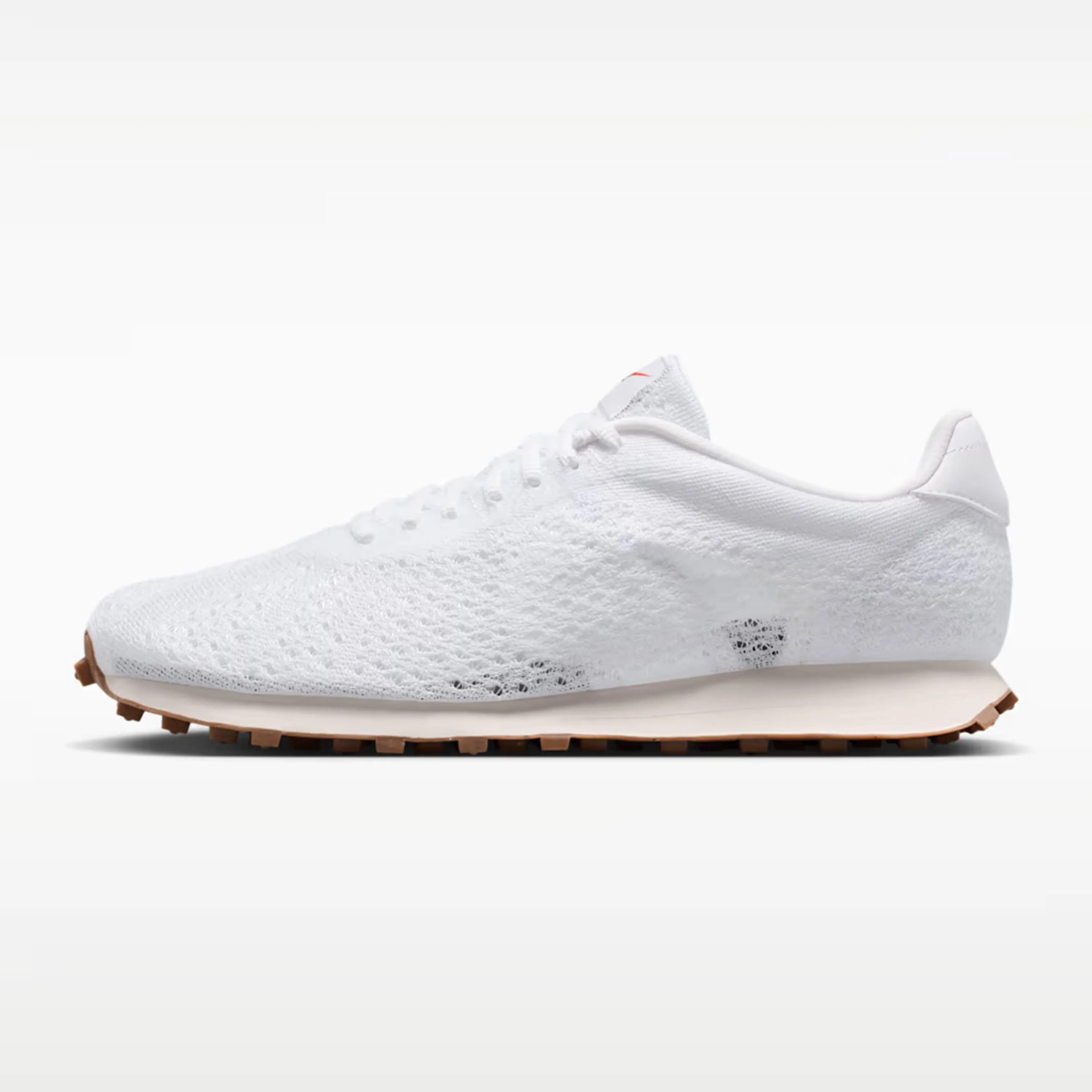 White knitted low-top sneaker with gum sole and white laces on a white background.