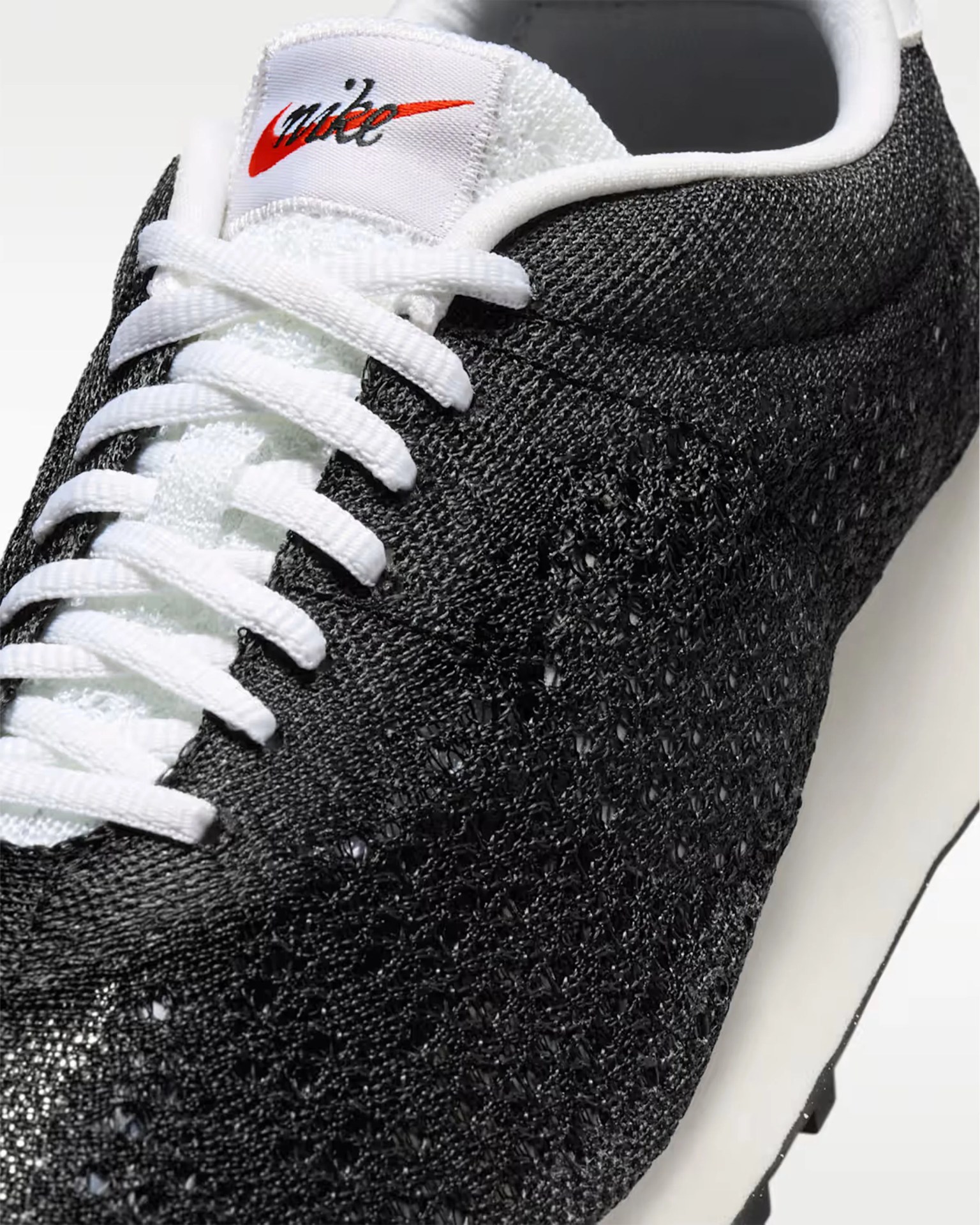 White knitted low-top sneaker with gum sole and white laces on a white background.