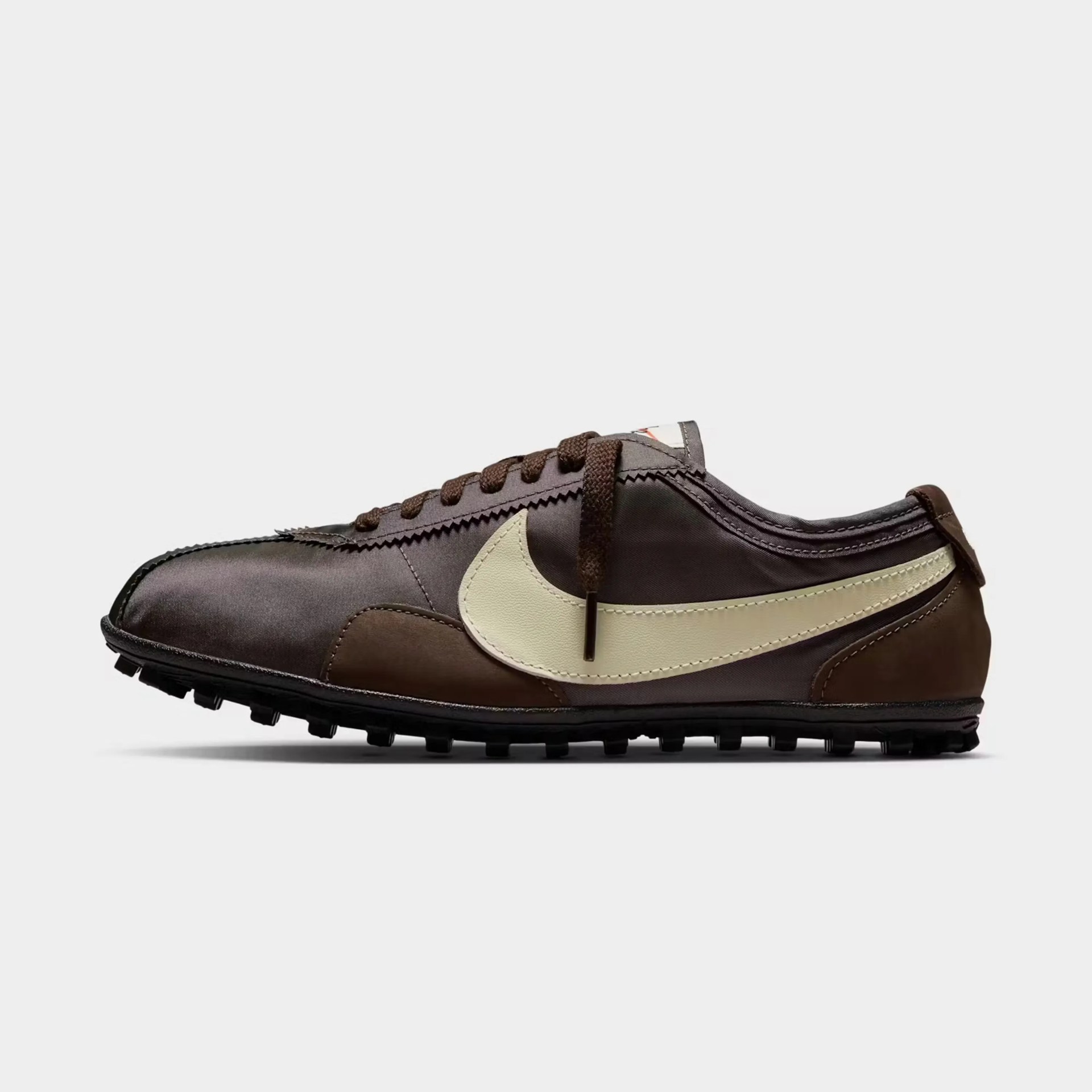 Brown and beige Nike sneaker with a textured sole and zigzag stitching details.