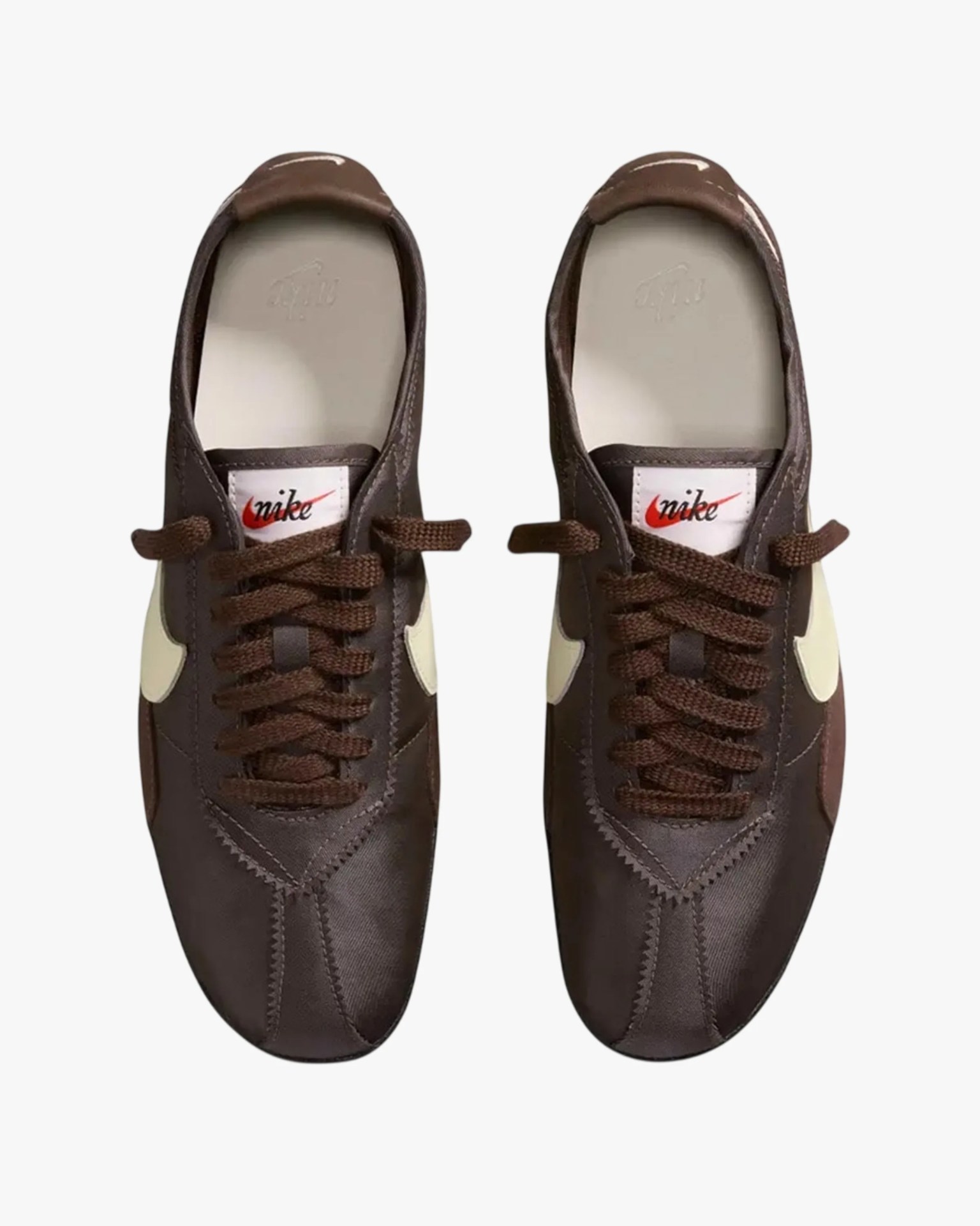 Pair of brown Nike sneakers with cream swoosh logos and brown laces viewed from above.