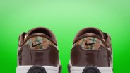 Pair of brown Nike sneakers with multicolor patterned heel and white soles against a green background.