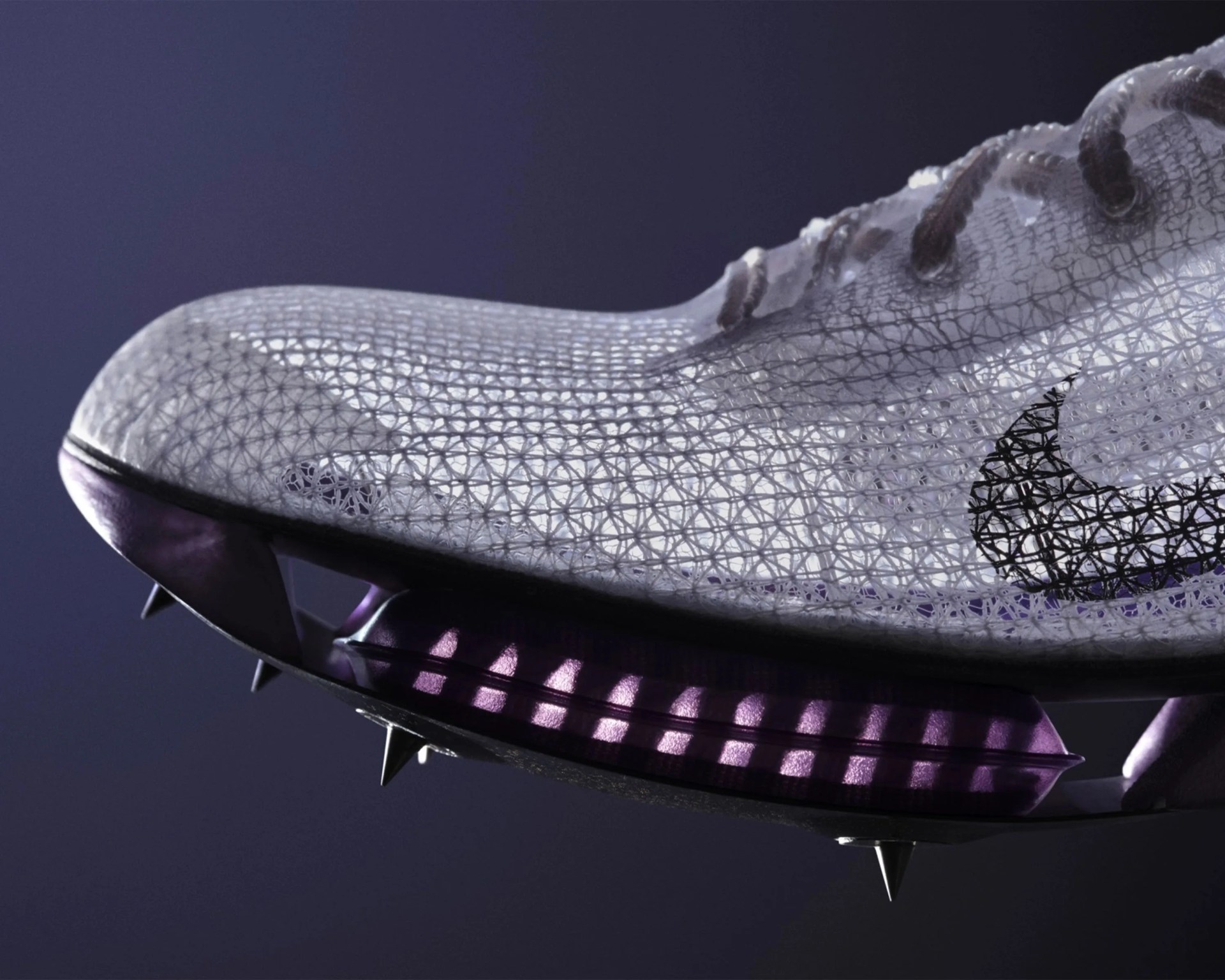 Close-up of a translucent soccer cleat with a geometric mesh pattern and purple sole studs.