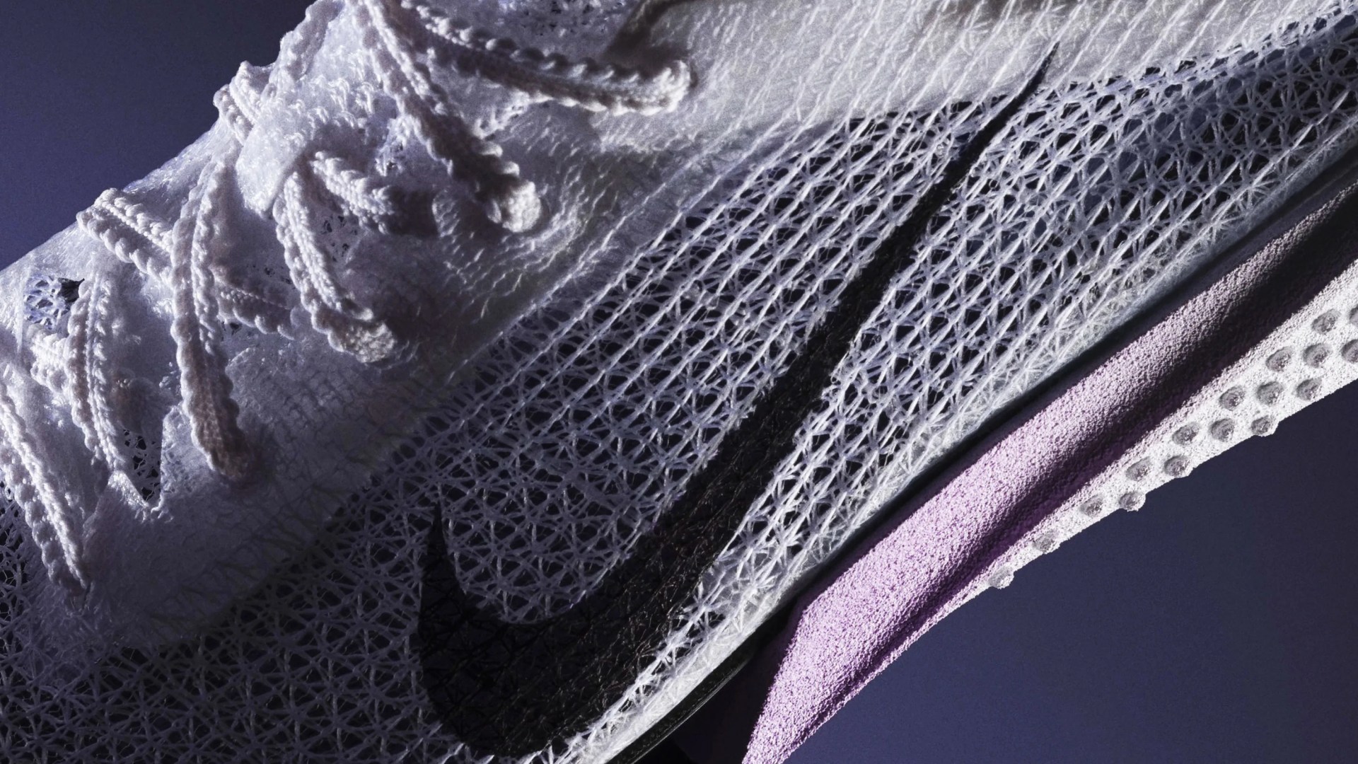 Close-up of a white Nike sneaker with a black swoosh and purple midsole, featuring a mesh upper and textured sole.