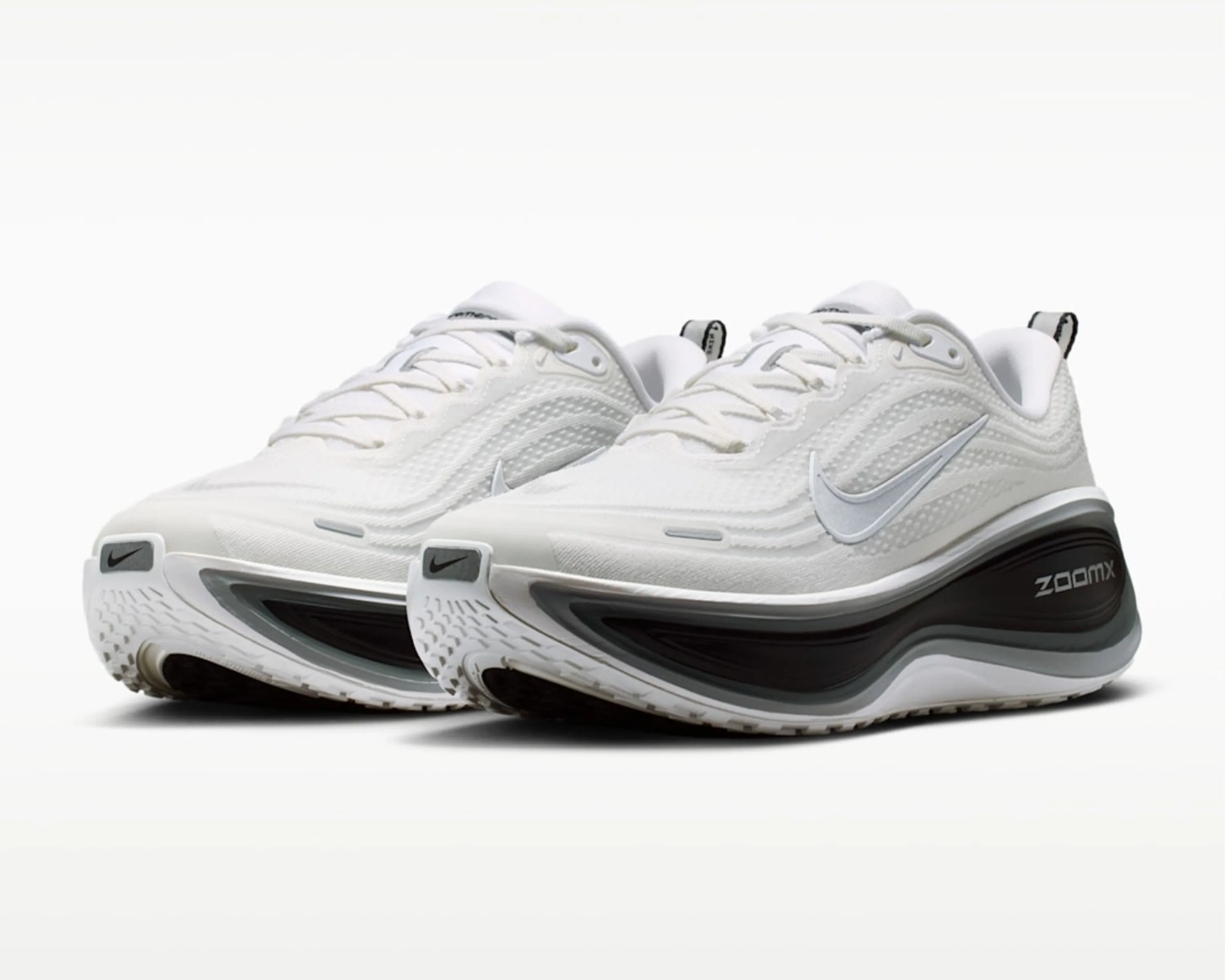 Pair of white Nike ZoomX running shoes with silver swoosh and black sole accents.