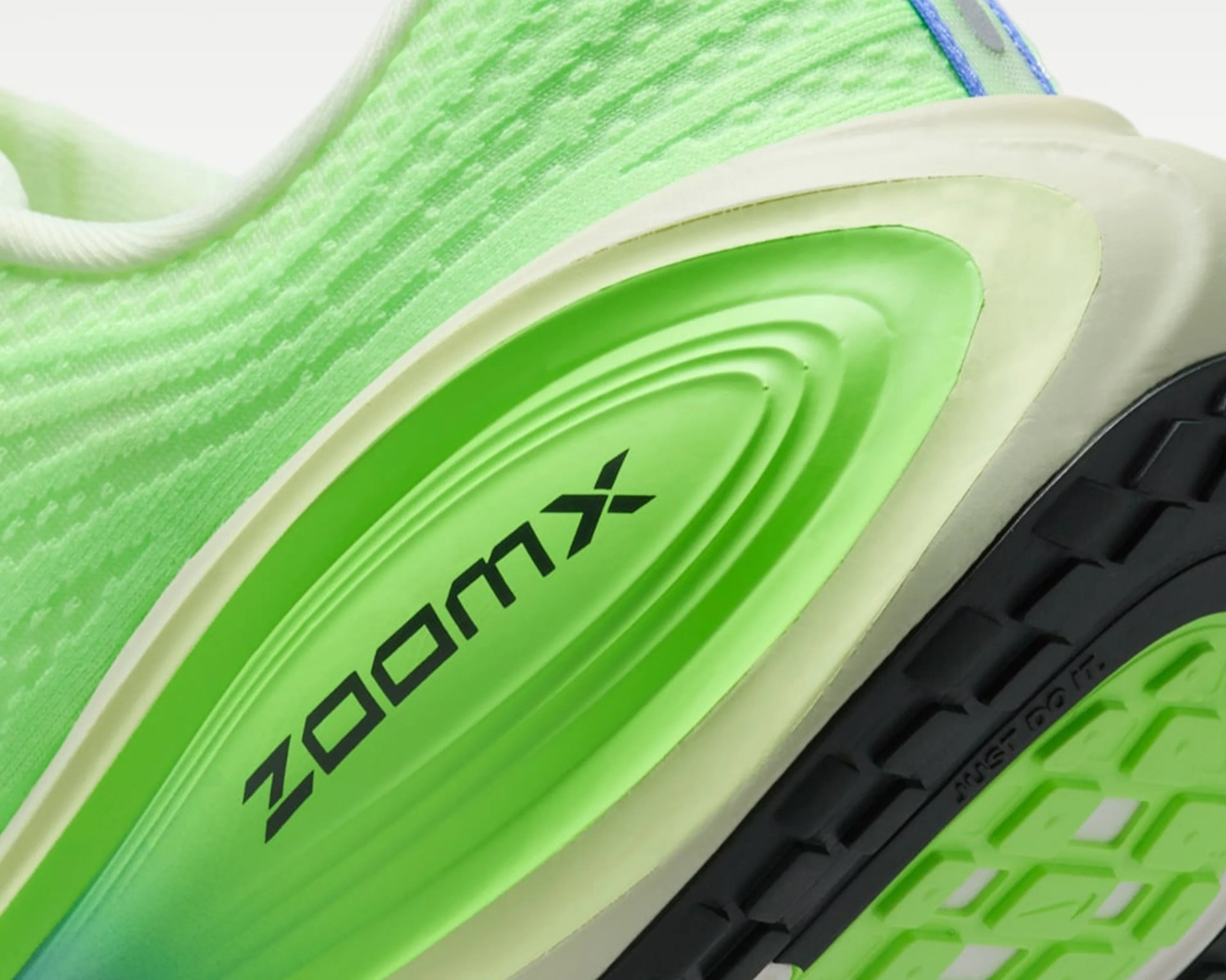 Close-up of a green and white sneaker sole with black text and textured black and green tread.