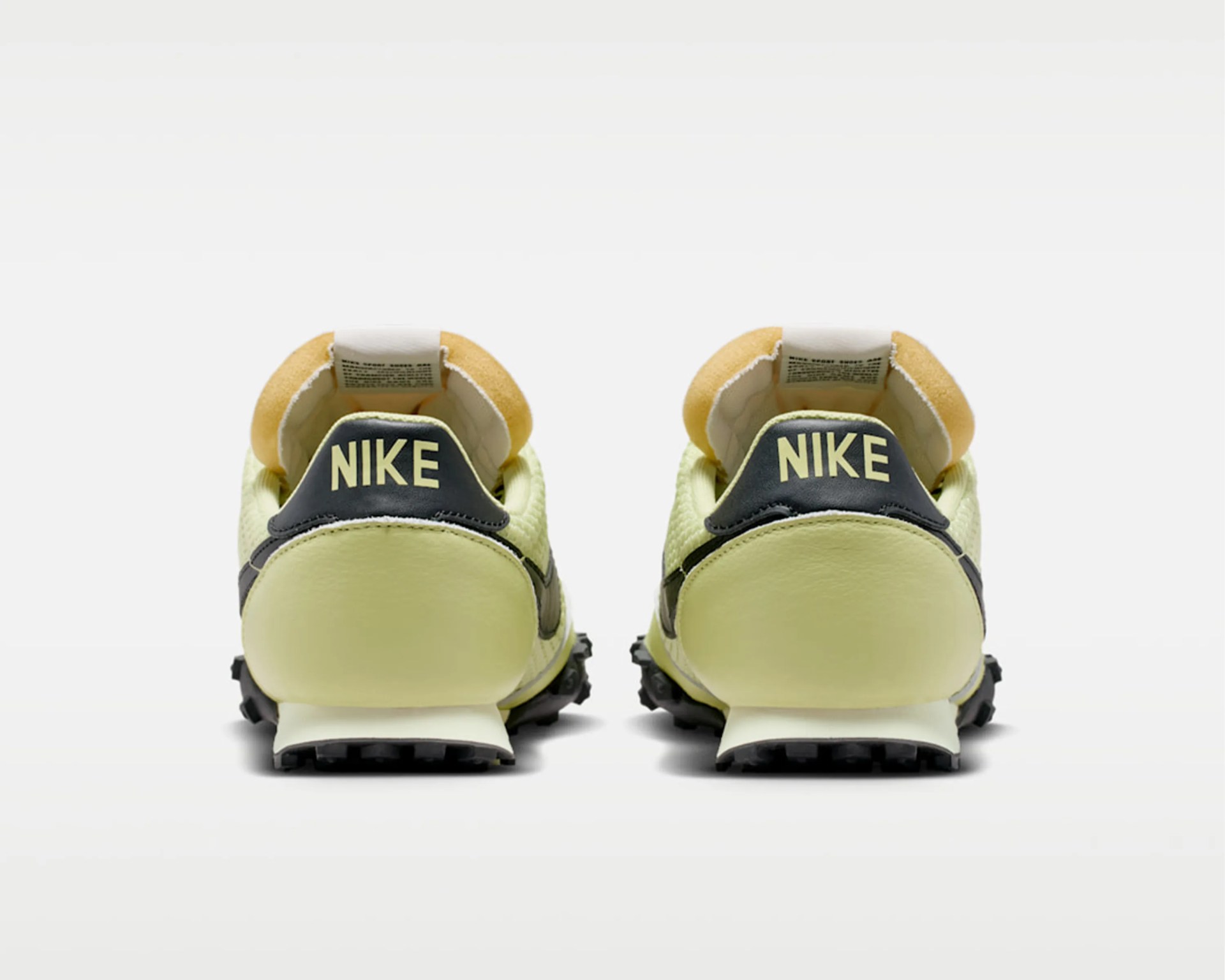 Pair of pale yellow Nike sneakers with black heel tabs and beige padded collars, viewed from the back.