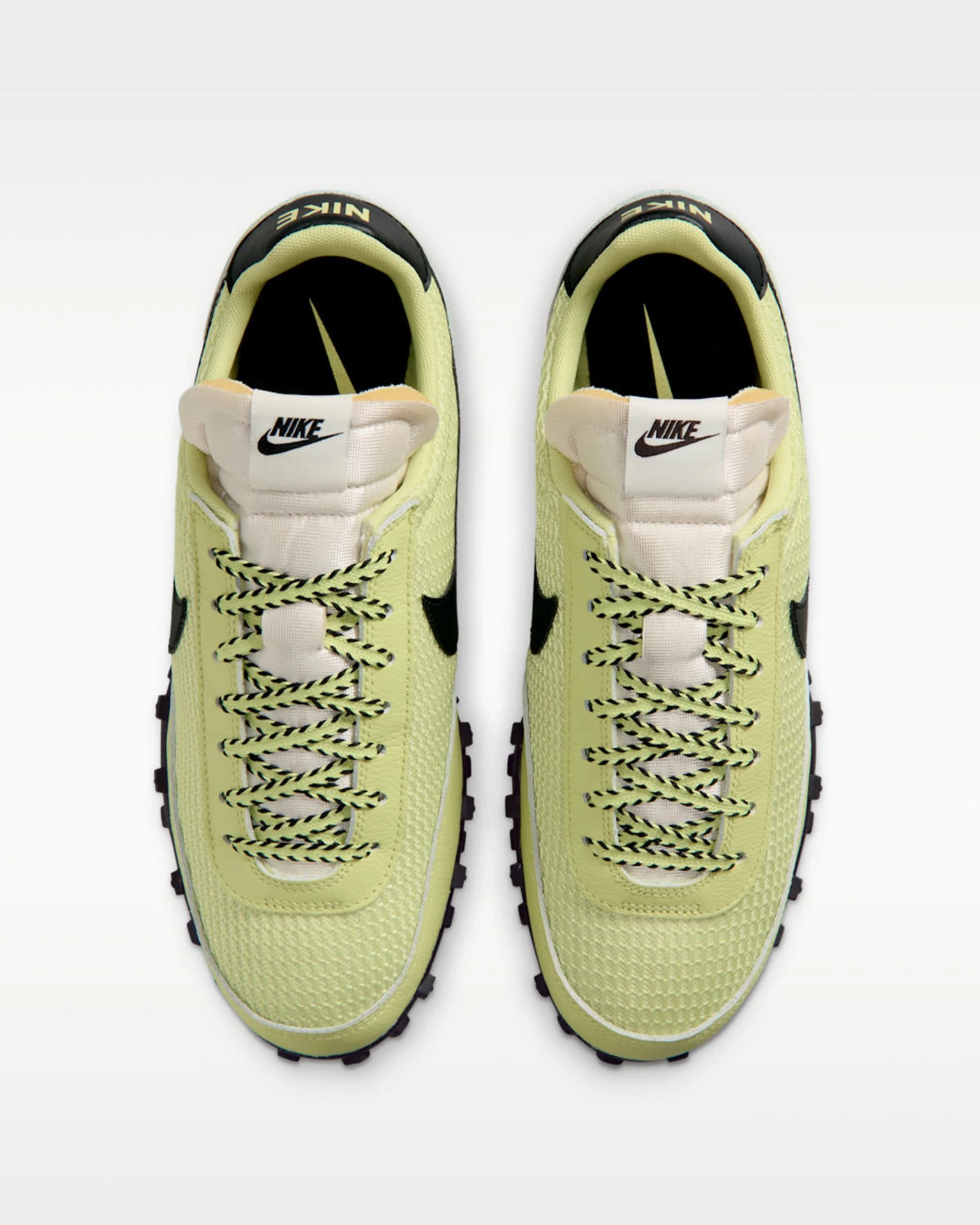 Pair of light green Nike sneakers with black swoosh logos and black-and-green laces viewed from above.