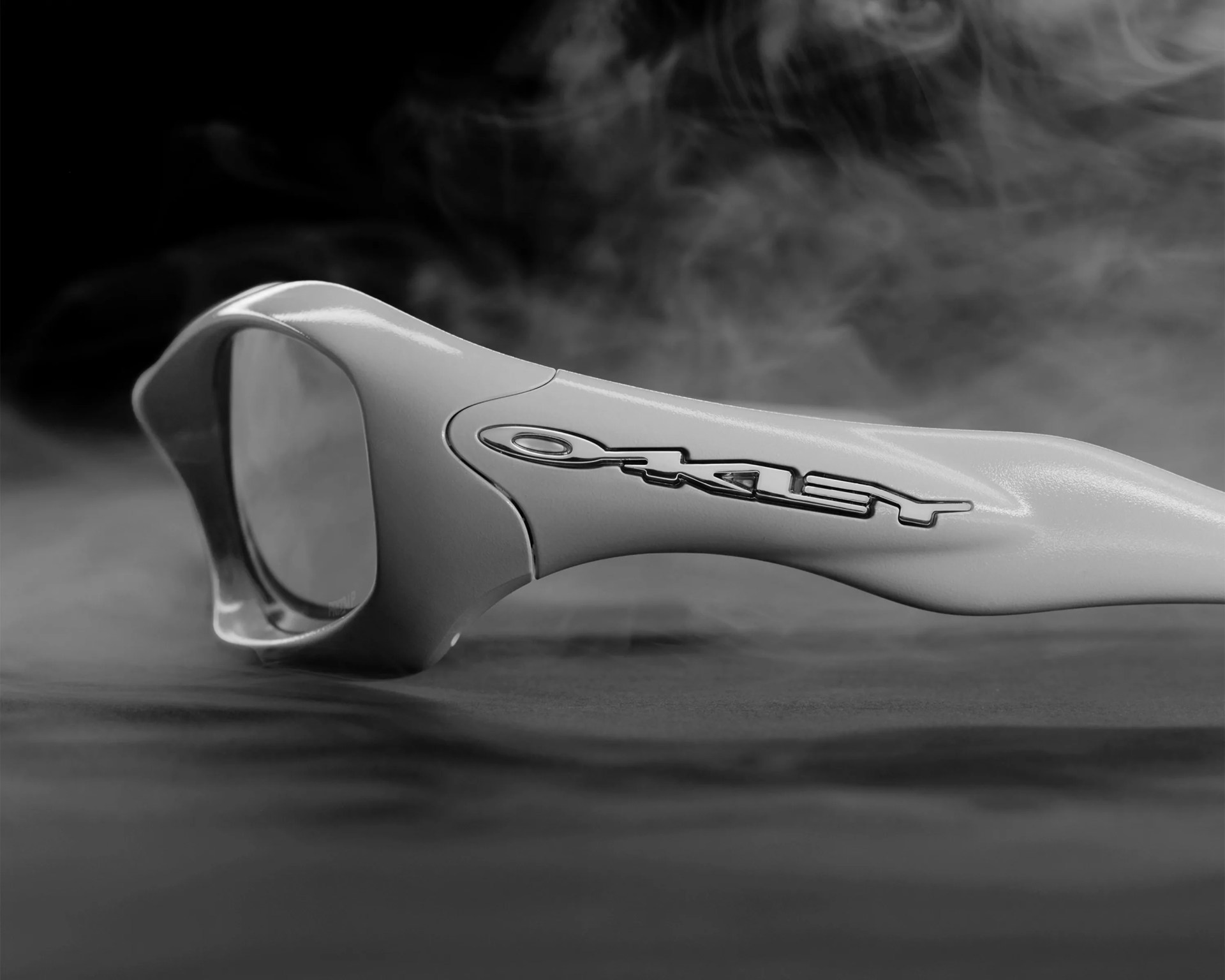 Close-up of white Oakley sunglasses arm with logo and smoky background.