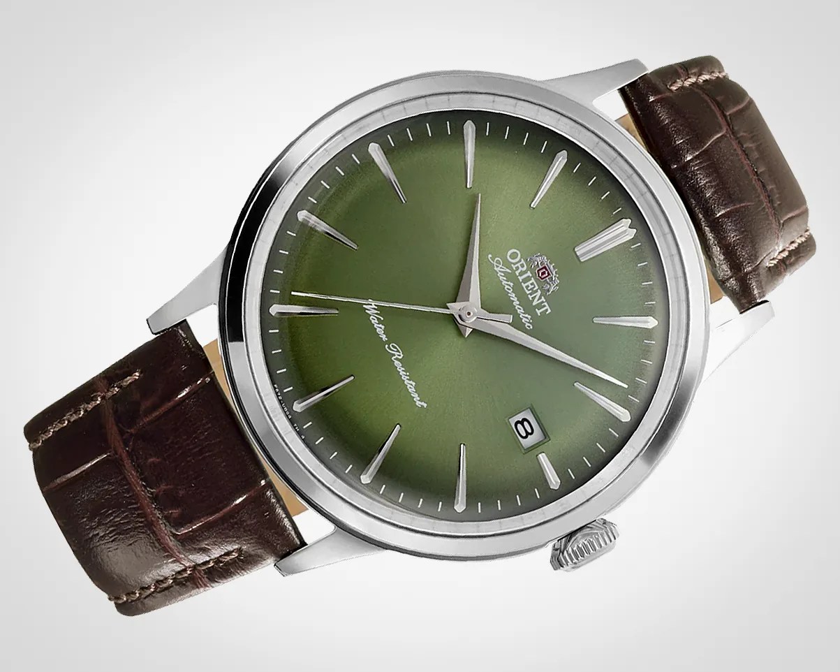 Silver Orient wristwatch with green dial, silver markers, date window, and brown leather strap.