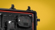 Black hard case with black and red interior organizer pouches against a yellow background.