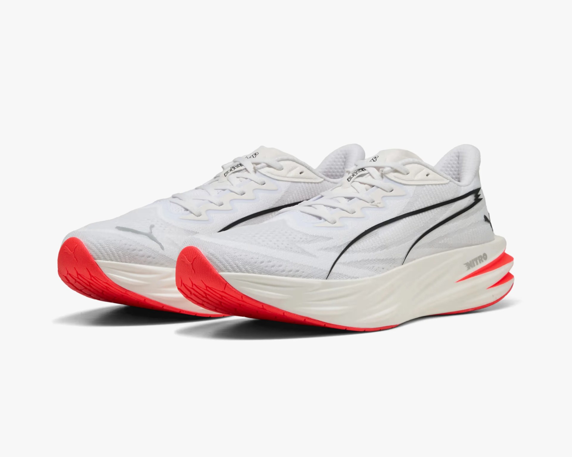 Pair of white Puma running shoes with black logo and bright red soles.