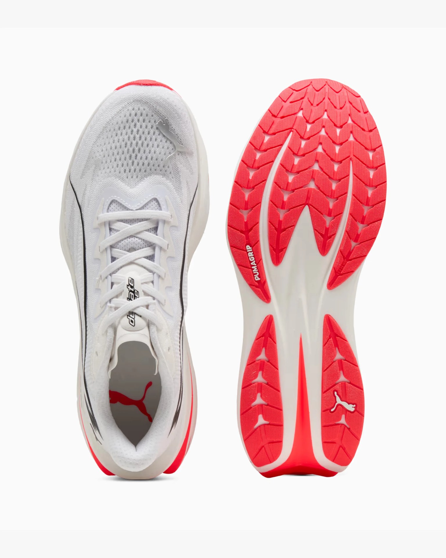 White Puma running shoe with mesh upper and bright red rubber sole showing PUMAGRIP tread pattern.