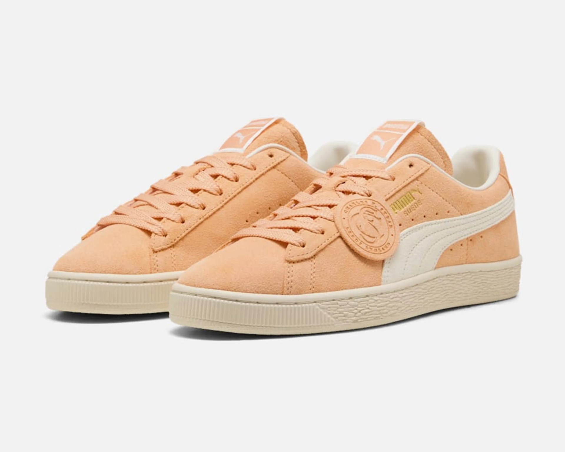 Peach suede Puma sneakers with white stripe and beige rubber sole.