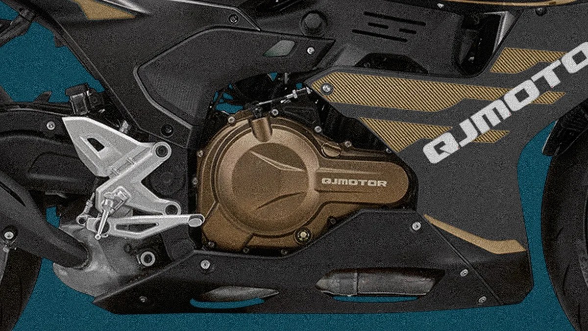 Close-up of a black and gold QJMotor motorcycle engine and footrest assembly.