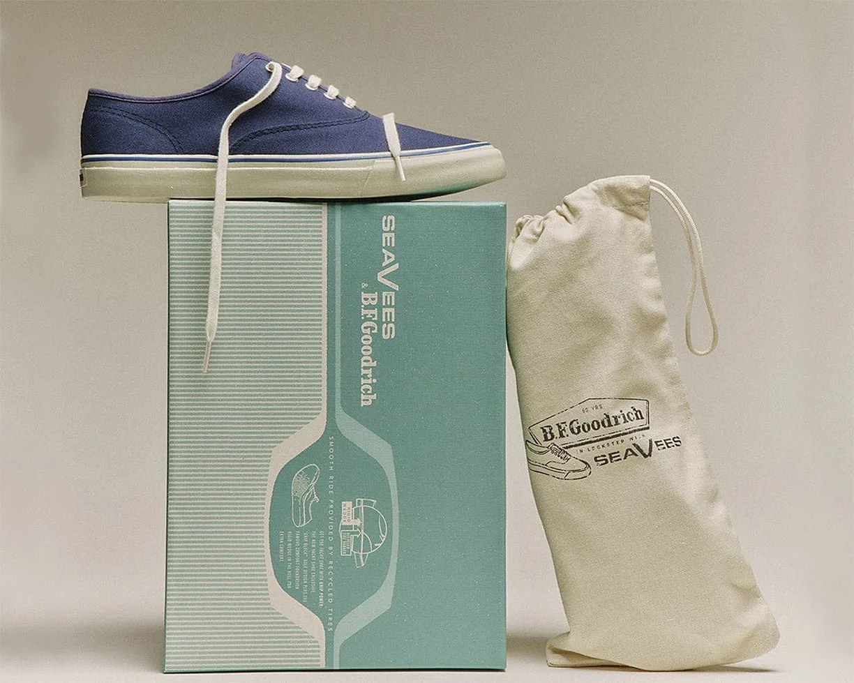 Navy canvas sneaker with white sole and laces on a teal SEAVEES & B.F. Goodrich shoe box next to a beige drawstring bag.