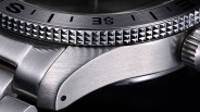 Close-up of a stainless steel watch case with a textured bezel and a crown on the right side.