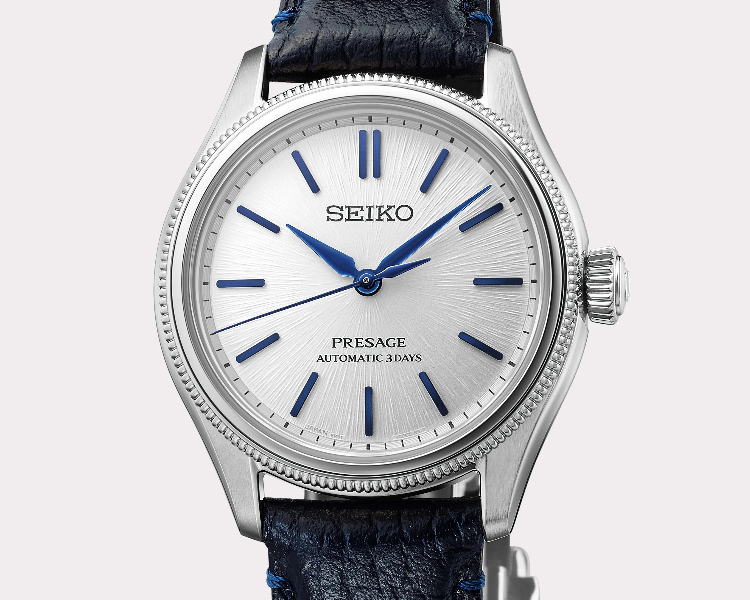 Silver Seiko Presage watch with blue hour markers and hands, and a textured dark blue leather strap.