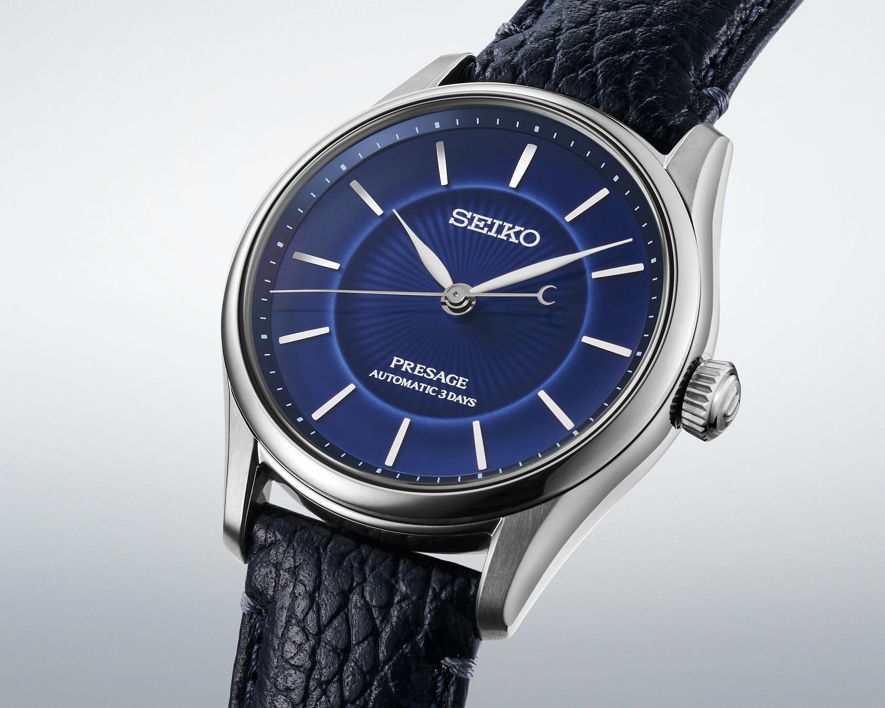 Seiko Presage watch with a deep blue dial, silver hour markers, and a textured dark blue leather strap.