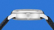 Side view of a silver stainless steel watch case with a crown marked "S" and black leather straps.