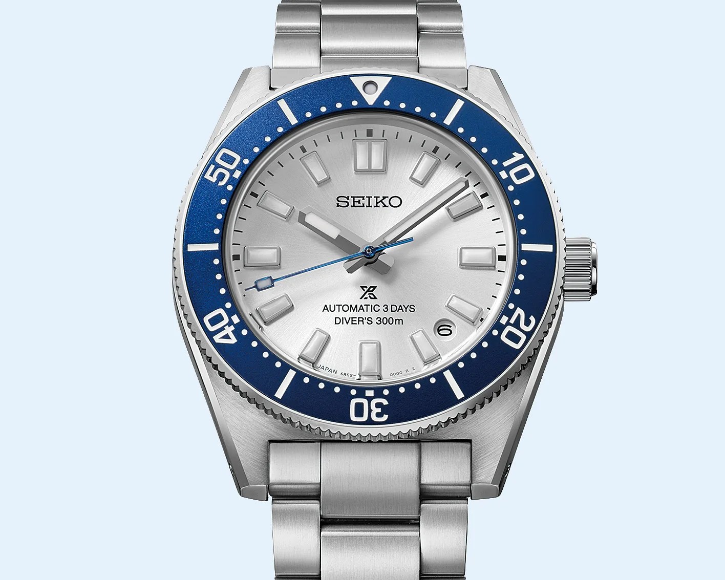 Silver Seiko diver's watch with blue bezel and stainless steel bracelet showing date at 4 o'clock.