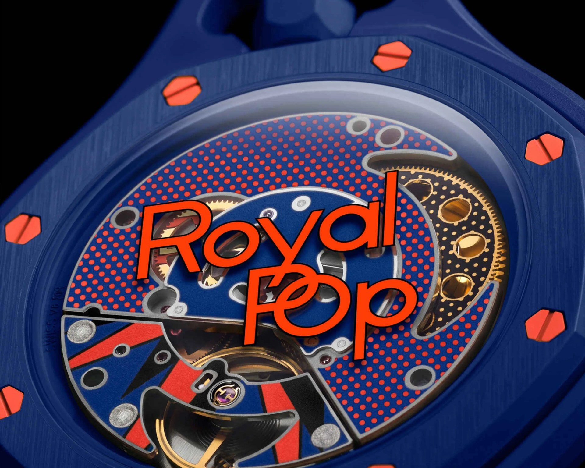 Close-up of a blue watch face with red screws, red and blue patterned dial, visible gears, and partially obscured orange text "Royal Oak".