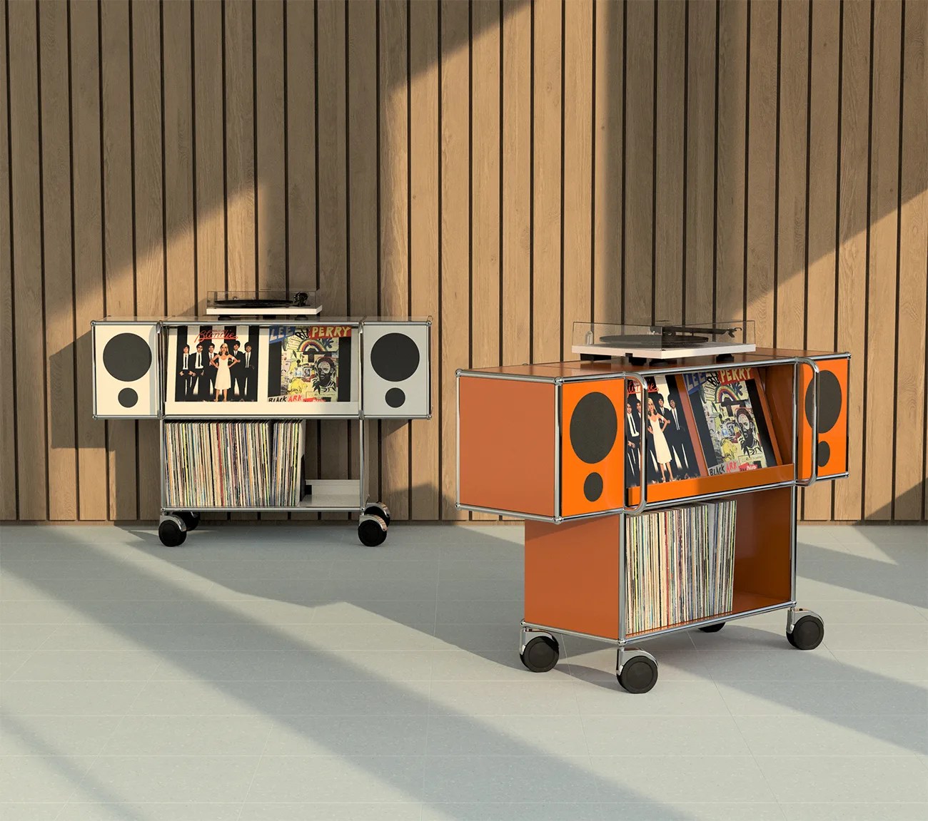 Two modern orange and white mobile record players with built-in speakers and vinyl records, set against a wooden paneled wall.