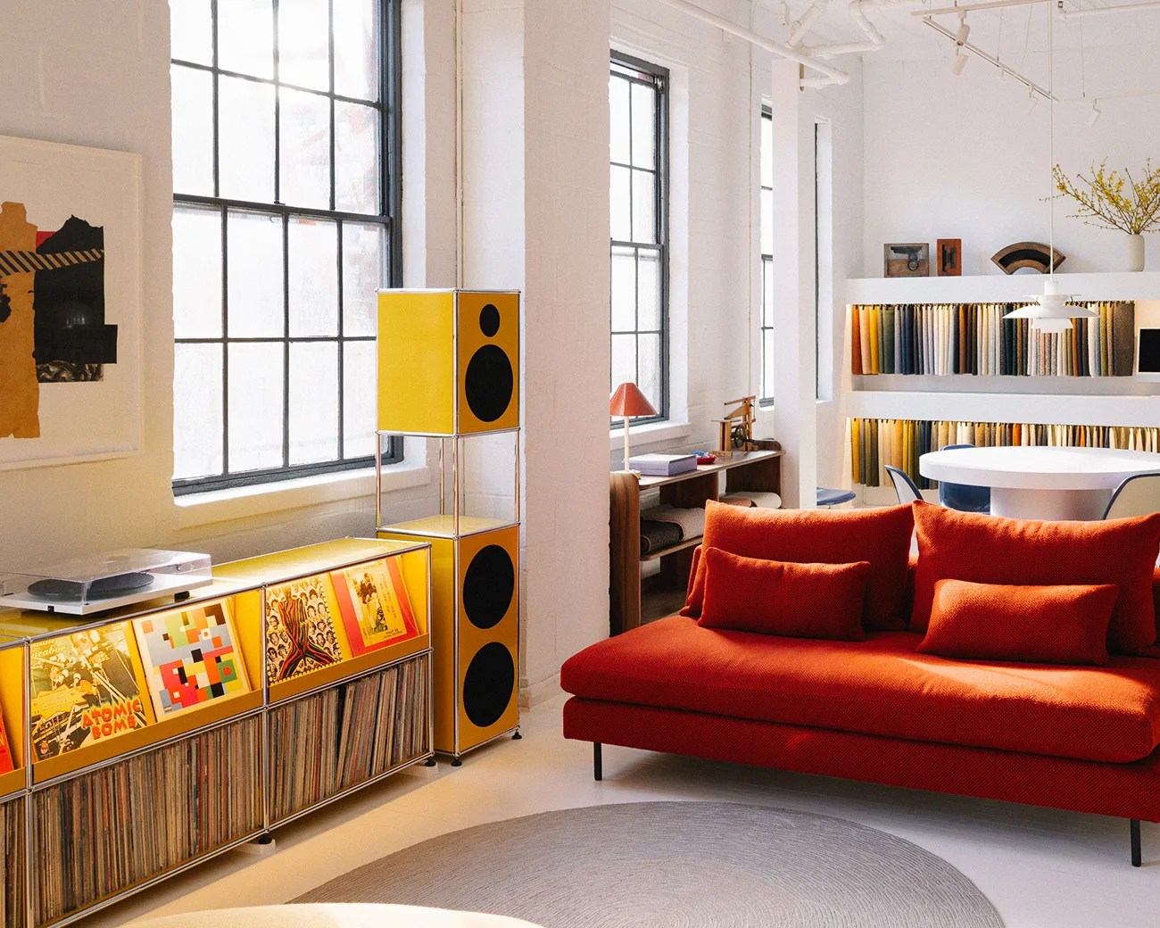 Bright orange sofa with matching cushions in a modern living room with yellow speakers and vinyl records.