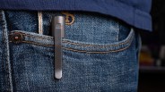 Slim black metal pen clipped to the front pocket of blue denim jeans worn with a navy shirt.