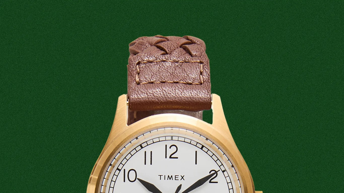 Gold-tone Timex wristwatch with white dial and black numerals, featuring a brown braided leather strap.