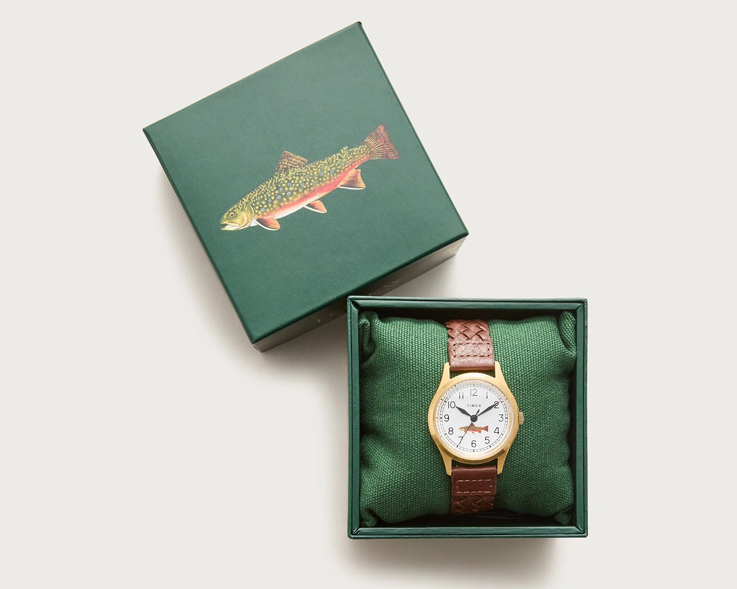 Gold-toned Timex wristwatch with white dial and brown braided leather strap in green box with fish illustration.