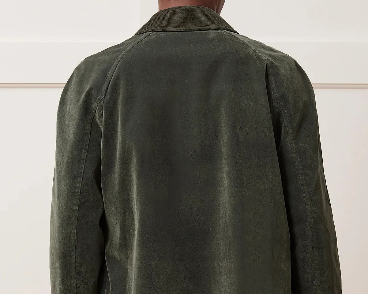 Back view of a dark olive green suede jacket with a corduroy collar worn by a person.