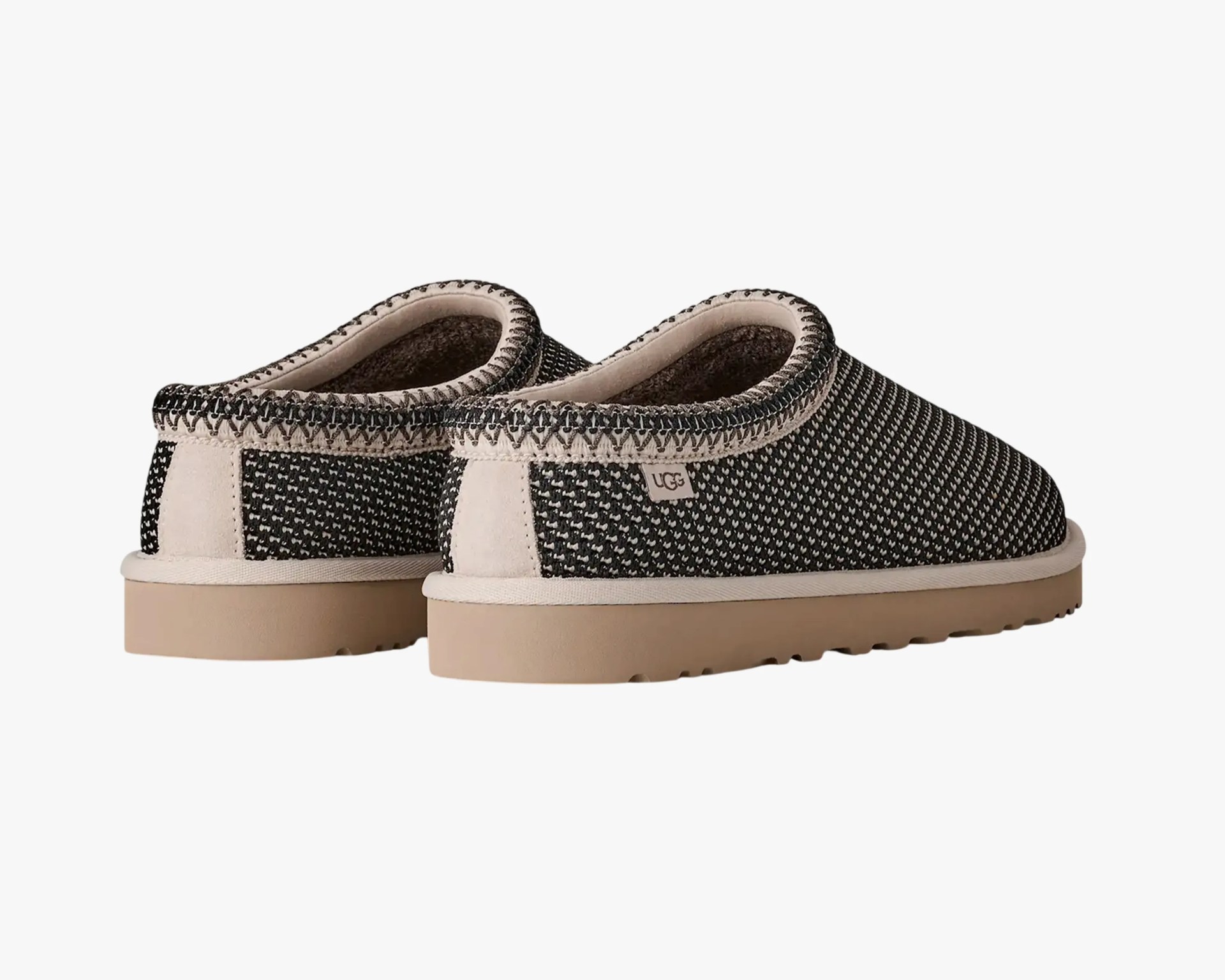 Pair of black and white knit UGG slippers with beige suede trim and light brown rubber soles.
